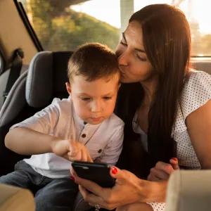 An infant in a car seat watching an smartphone screen with his mom